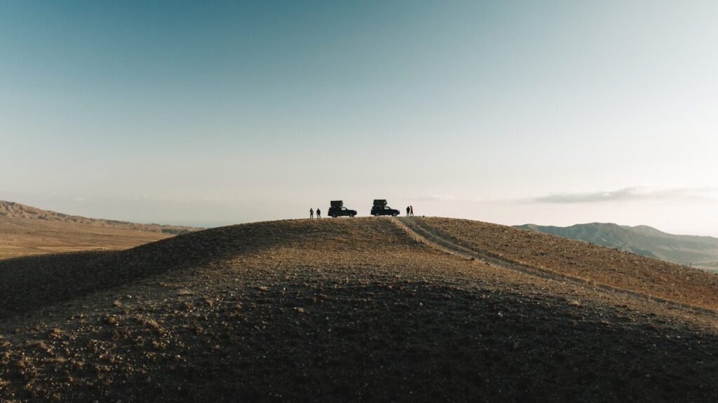 Two vehicles parked on a hilltop with people